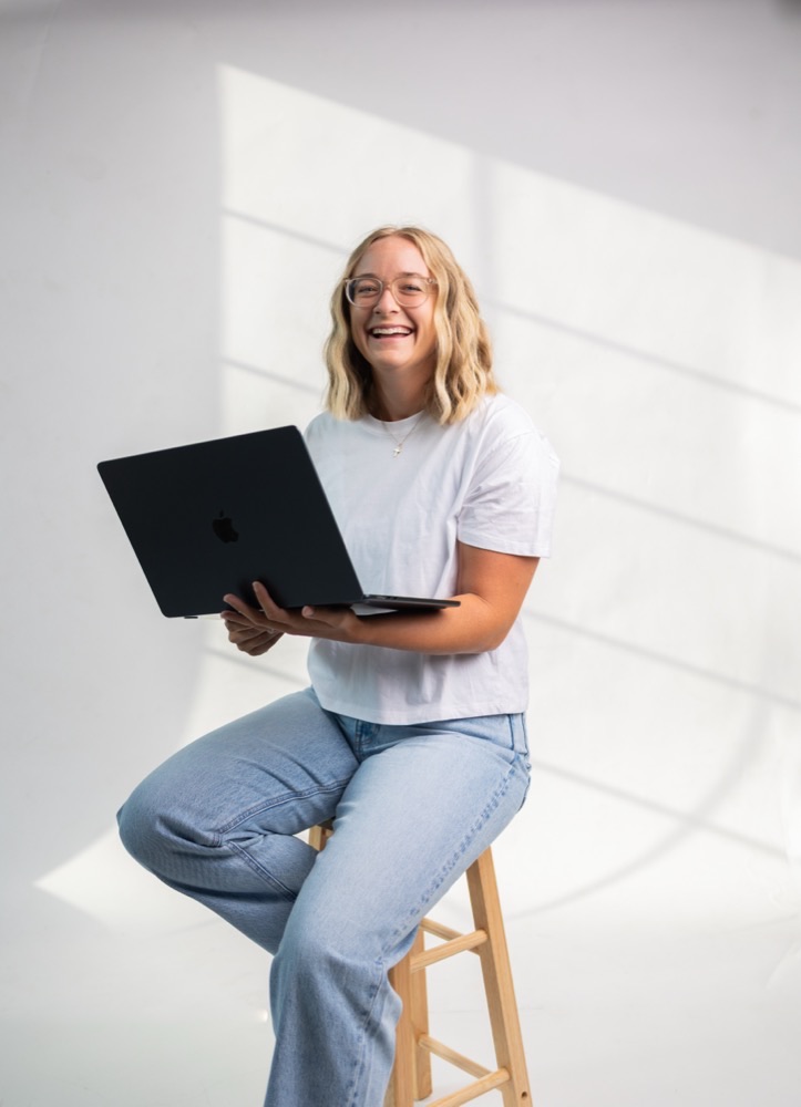 Christina Hedges smiling, holding a laptop
